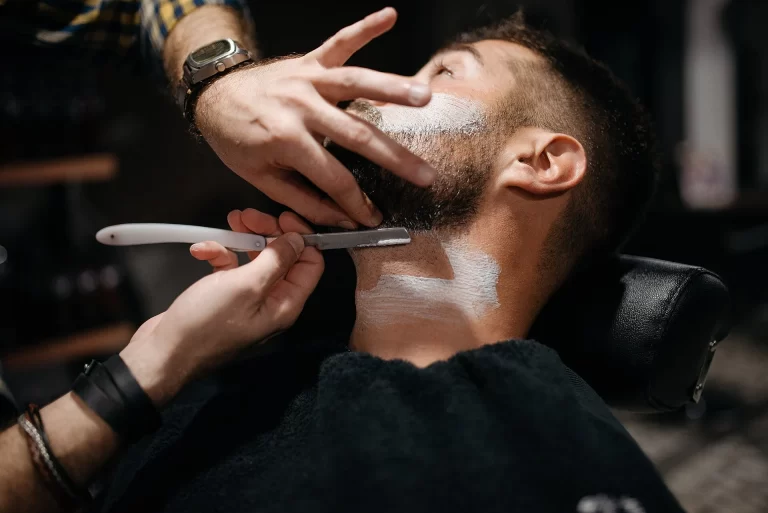 barber shaving a man's beard representing beard grooming