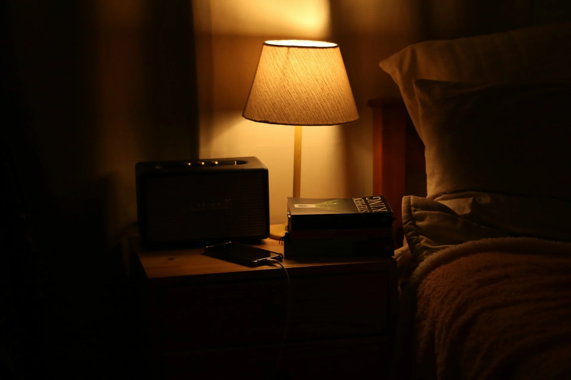 white noise machine running on a nightstand next to a bed