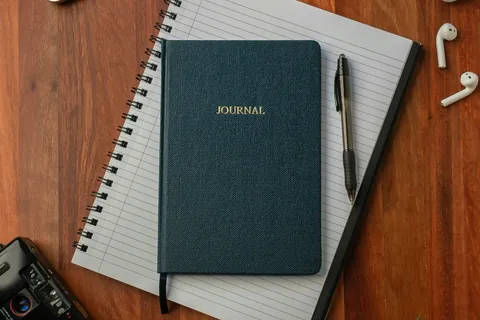 black spring notebook brown wooden table illustrating atomic habits vs tiny habits