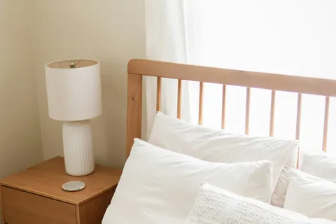 bright bedroom white bedding wooden headboard nightstand illustrating caffeine vs naps