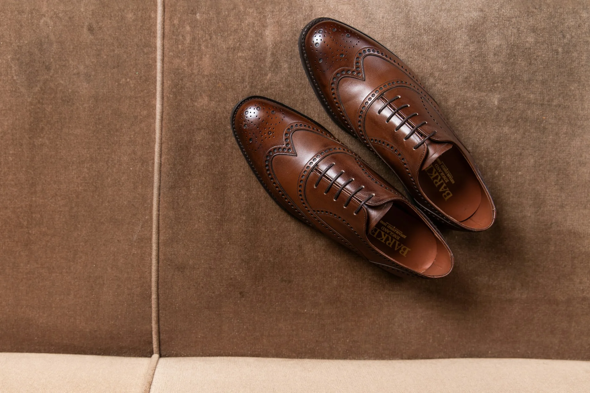 dark brown leather shoes placed next to a matching leather belt