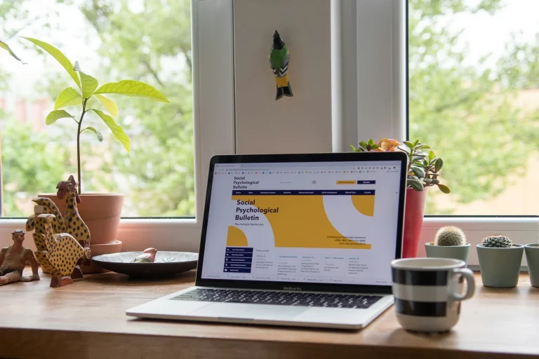 laptop displaying website wooden desk potted plants illustrating index funds vs stock picking