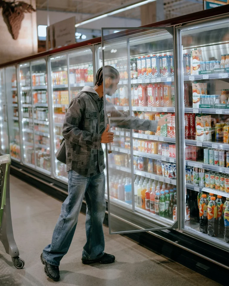 man choosing drinks refrigerated grocery store display illustrating magnesium vs melatonin for sleep