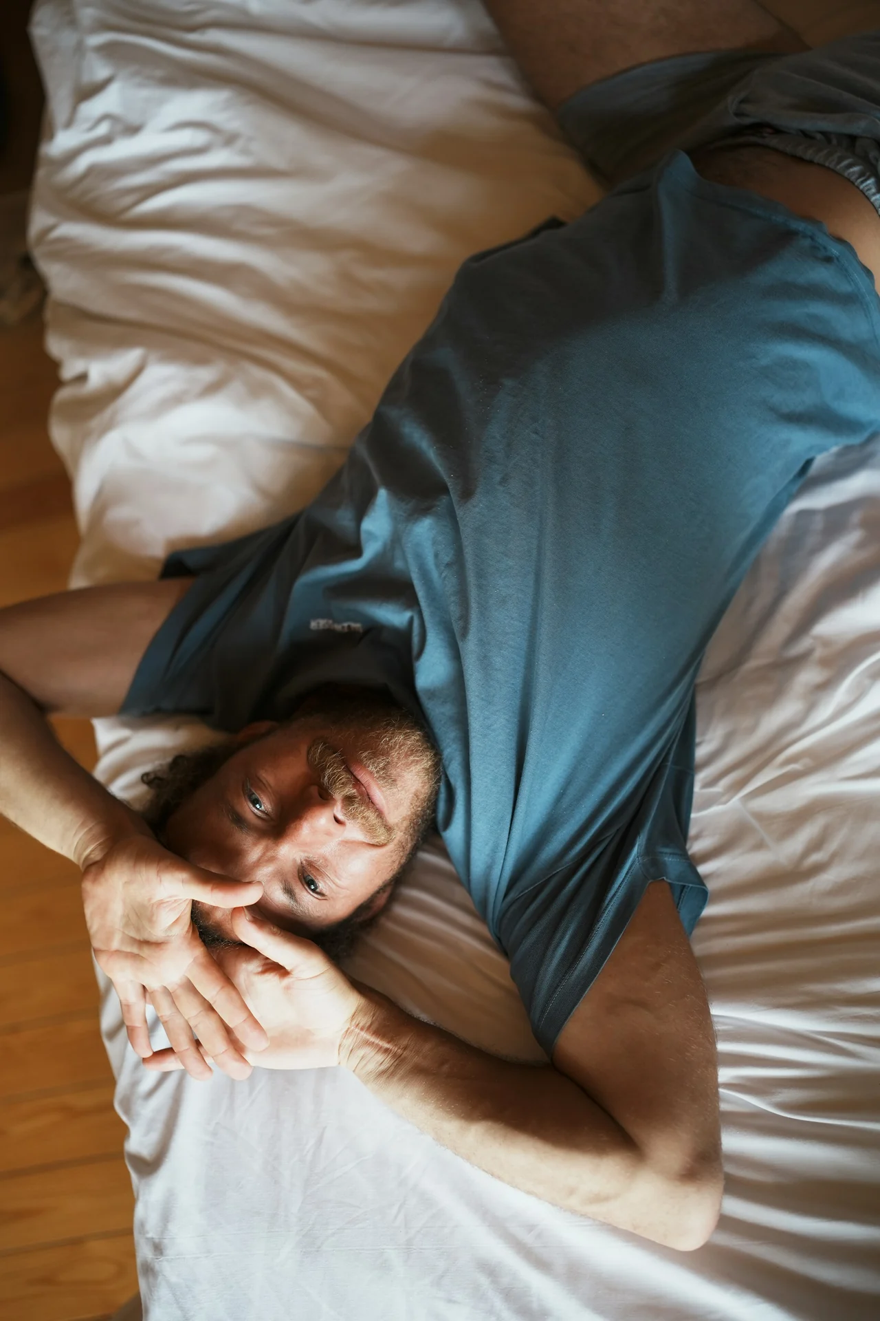side sleeper resting with a pillow between his knees in a bright bedroom