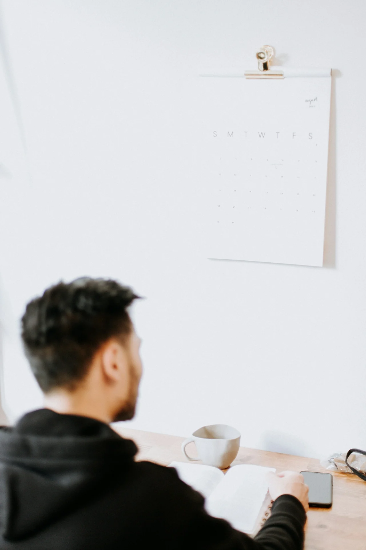 cup of black coffee on a desk beside a wall clock