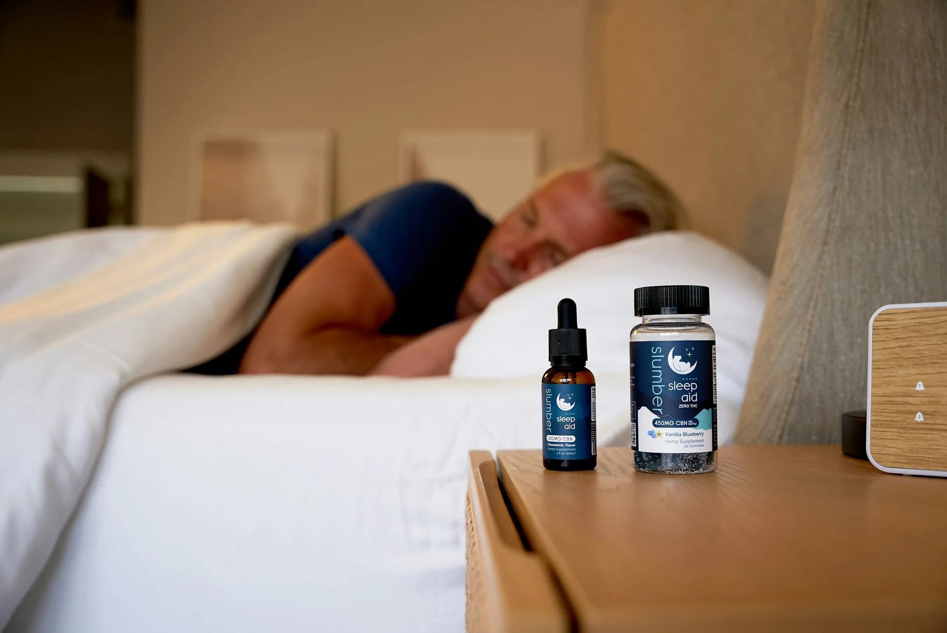 supplement bottle next to a small clock on a bedside table in dim light