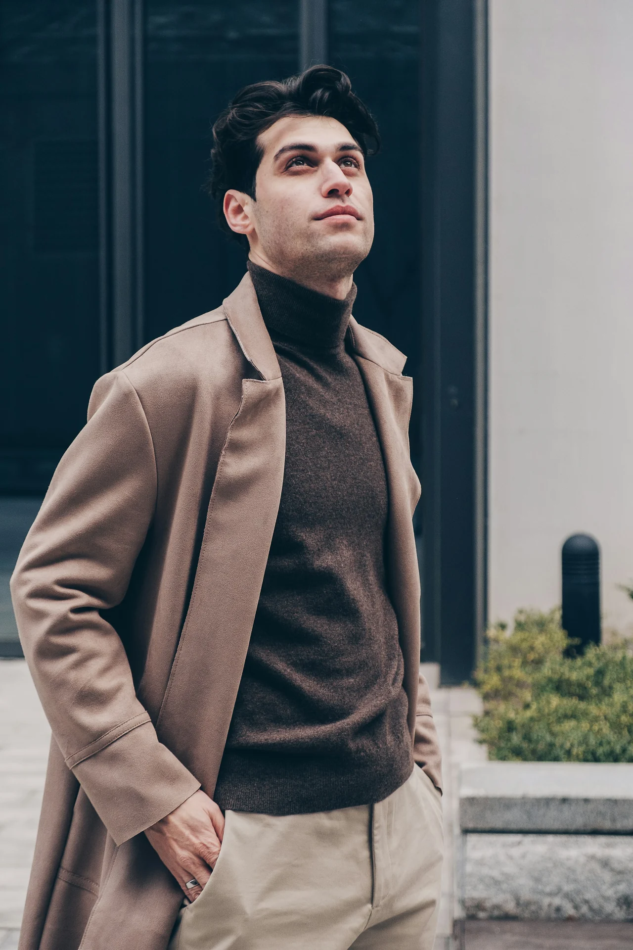 man buttoning a wool overcoat over a merino knit sweater