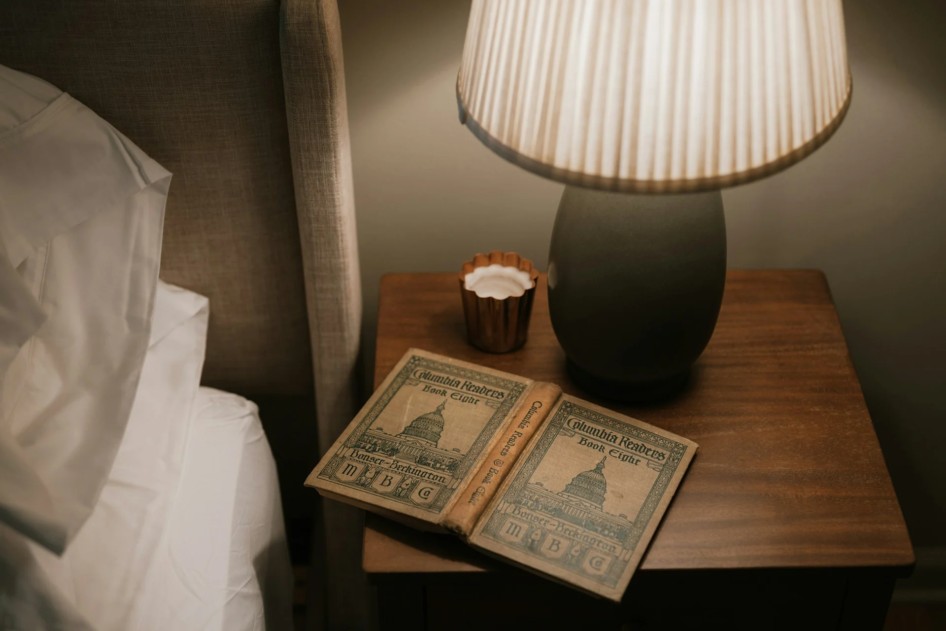 man writing his bedtime into a small notebook on a bedside table in dim light