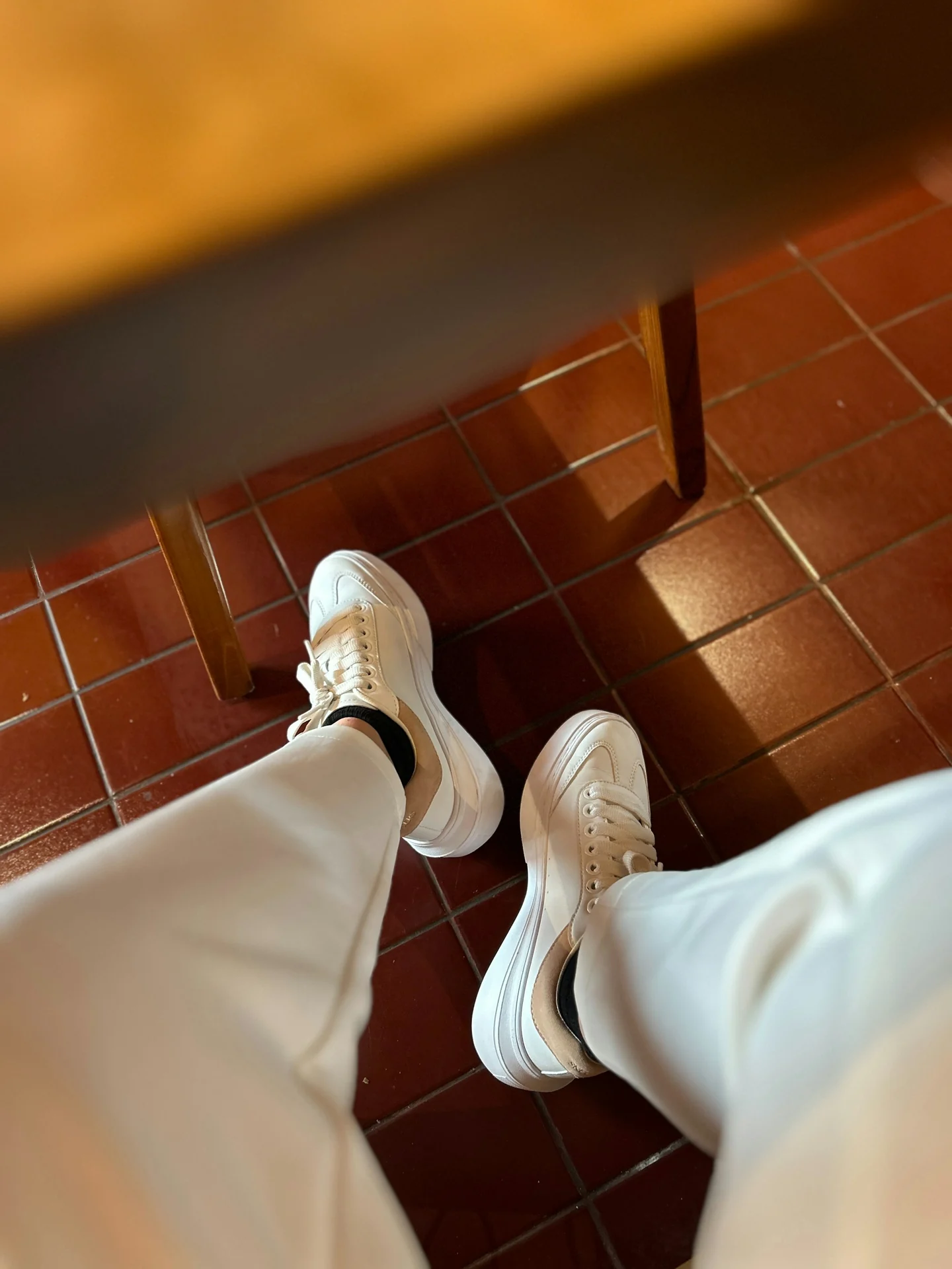 man standing in slim gray trousers and low-profile white leather sneakers