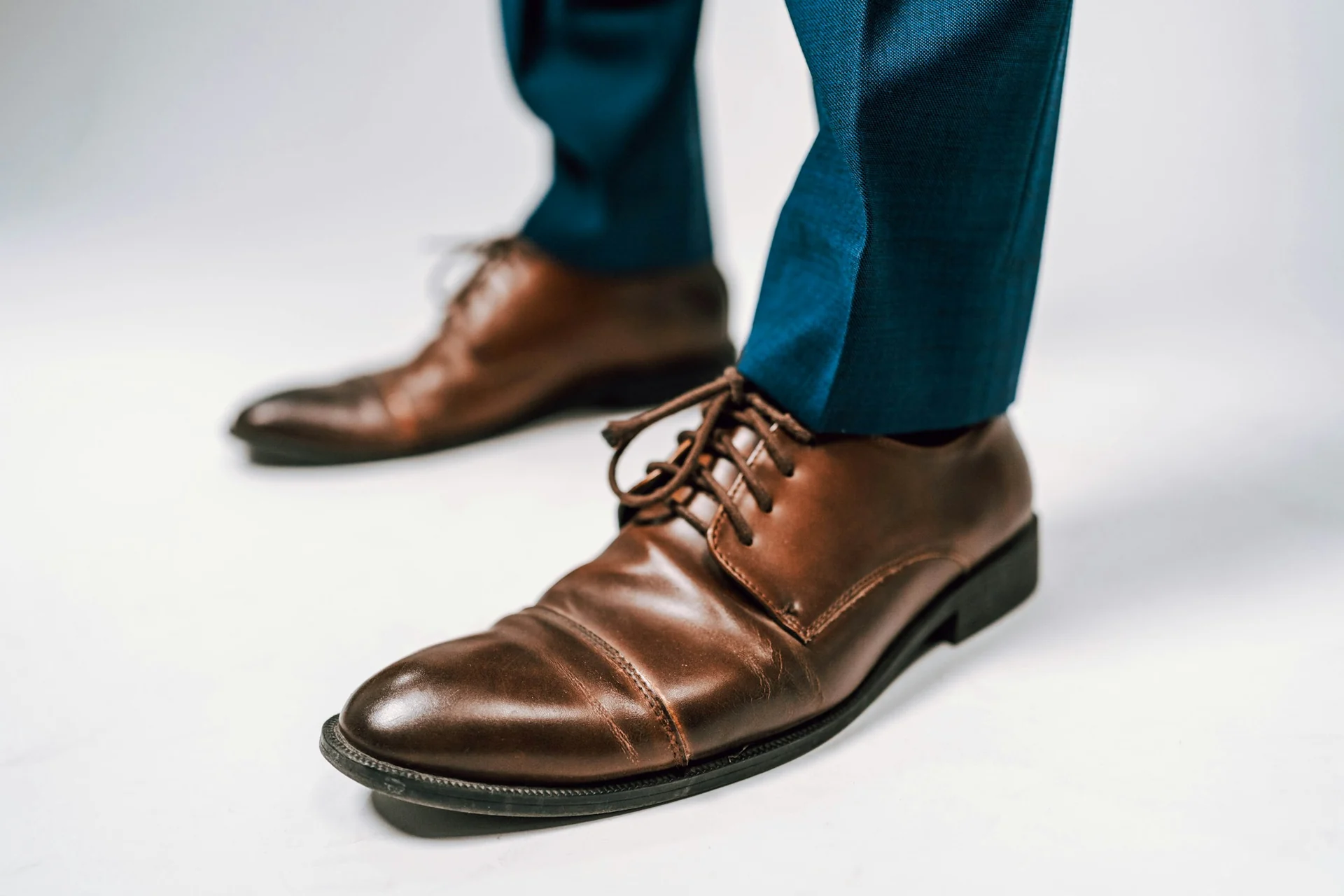 man standing in navy wool trousers and brown leather derby shoes