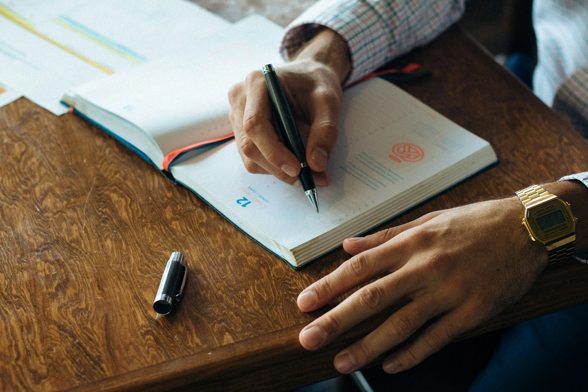 man writing a short habit list in a notebook at a kitchen table in the morning