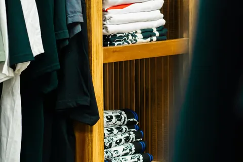 stack folded clothes wooden shelves illustrating chinos vs jeans