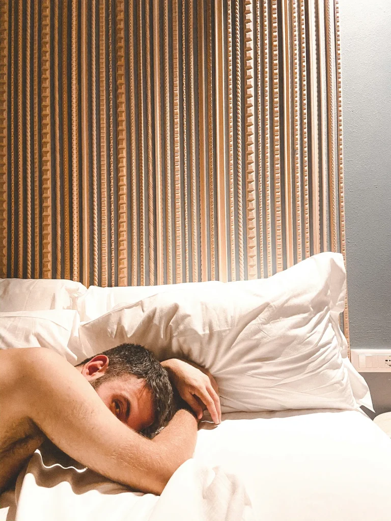 topless man lying bed illustrating how to sleep next to a snorer without waking up