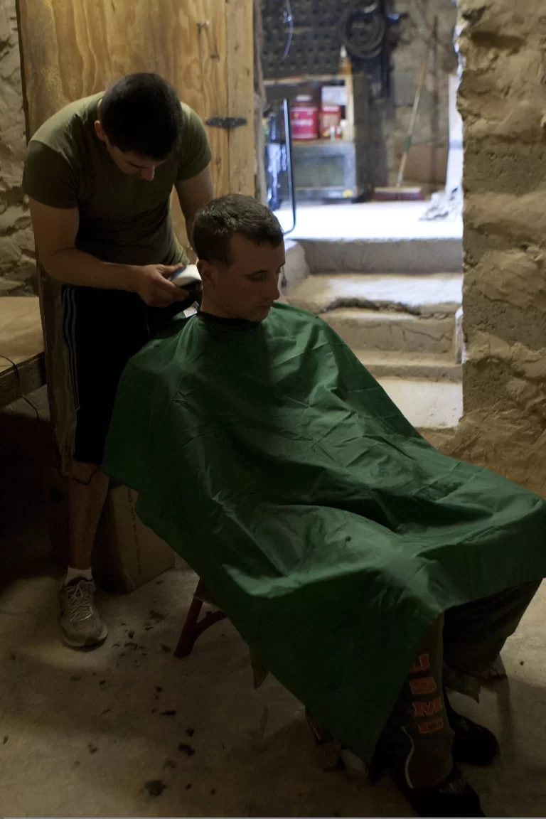 a U.S. Marine receiving a haircut at an outpost representing hair care