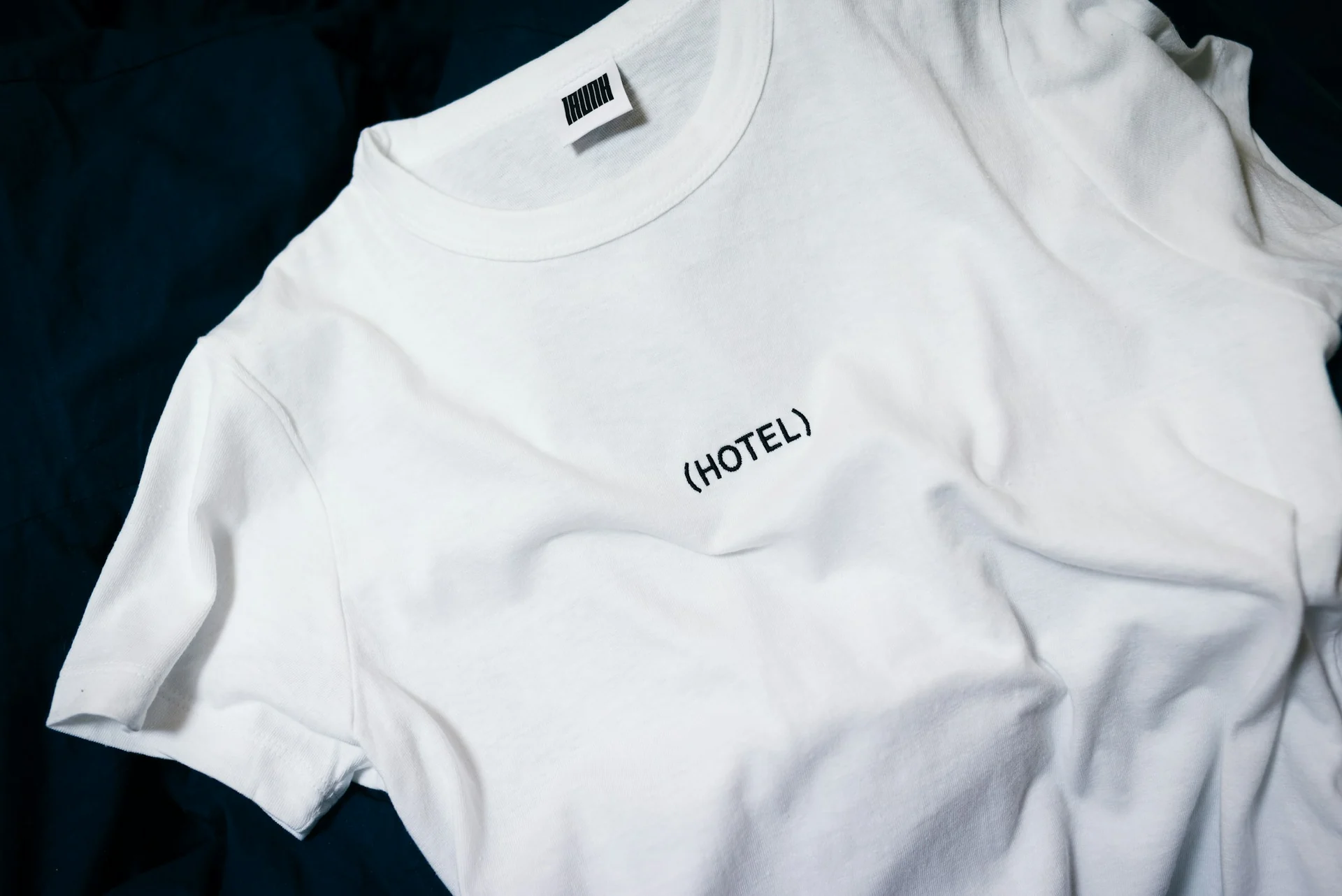 stack of folded white cotton t-shirts on a wooden shelf