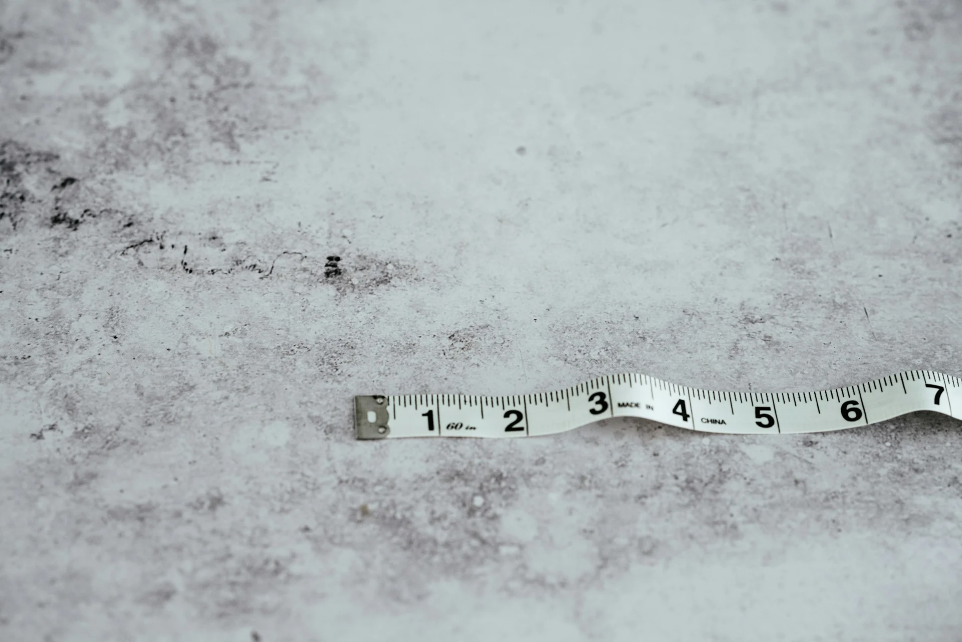 man measuring the width of his own shoulders with a tape measure in a bedroom