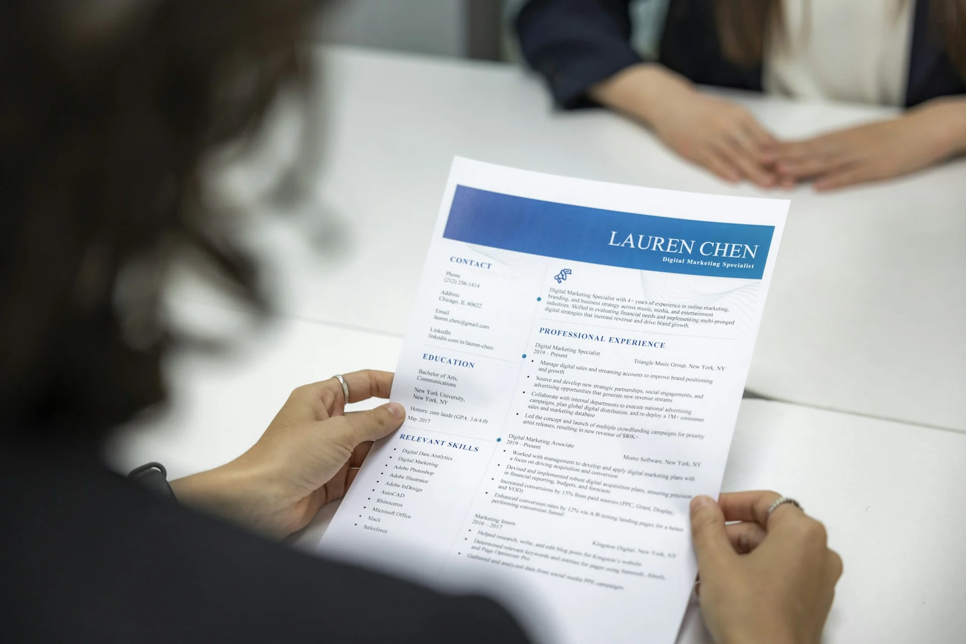 recruiter skimming a printed resume with a pen at a desk